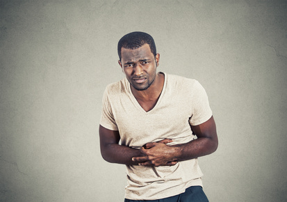 Man with stomach pain on gray wall background